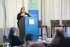 a woman standing at a podium with microphones
