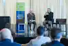 two men sitting on chairs in front of a crowd