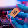 a hand in blue gloves holding a microchip