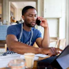 a man on the phone and looking at a laptop