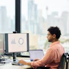 a man sitting at a desk with multiple computers