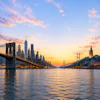 a bridge over water with city buildings and a sunset