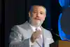 a man in a suit and tie speaking into a microphone
