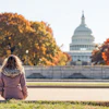 a woman sitting on the ground in front of a white building