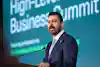 A person in a suit speaks at a podium during a High-Level Business Summit.
