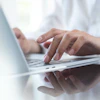 a close-up of a person's hands typing on a laptop