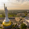 a statue of a woman with a torch on top of a gold dome