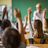 a group of children raising their hands in a classroom