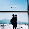 Man stands with daughter in airport watching a plane take off