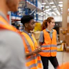 a group of women in orange vests in a warehouse