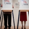 a man and woman standing in a room with voting boxes