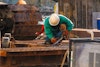 a man wearing a hard hat and gloves working on a metal structure