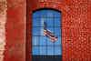U.S. flag reflected in the window of a red brick building