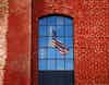 U.S. flag reflected in the window of a red brick building