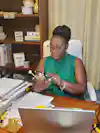 a woman sitting at a desk holding a phone